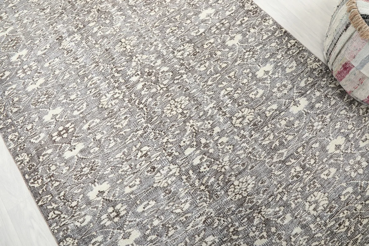 Detailed angle view of the rug's full pattern and soft gray and ivory colors