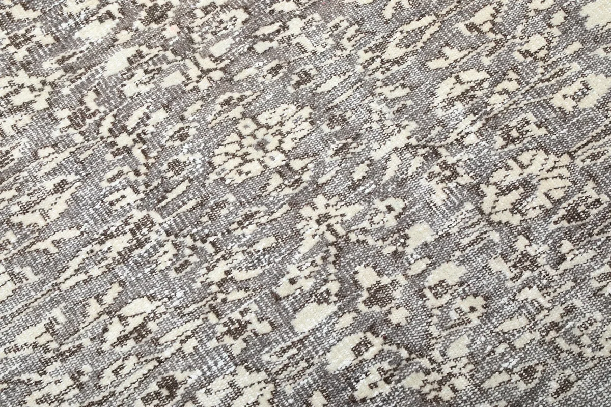 Close-up detail of the hand-knotted pile and distressed floral and geometric patterns
