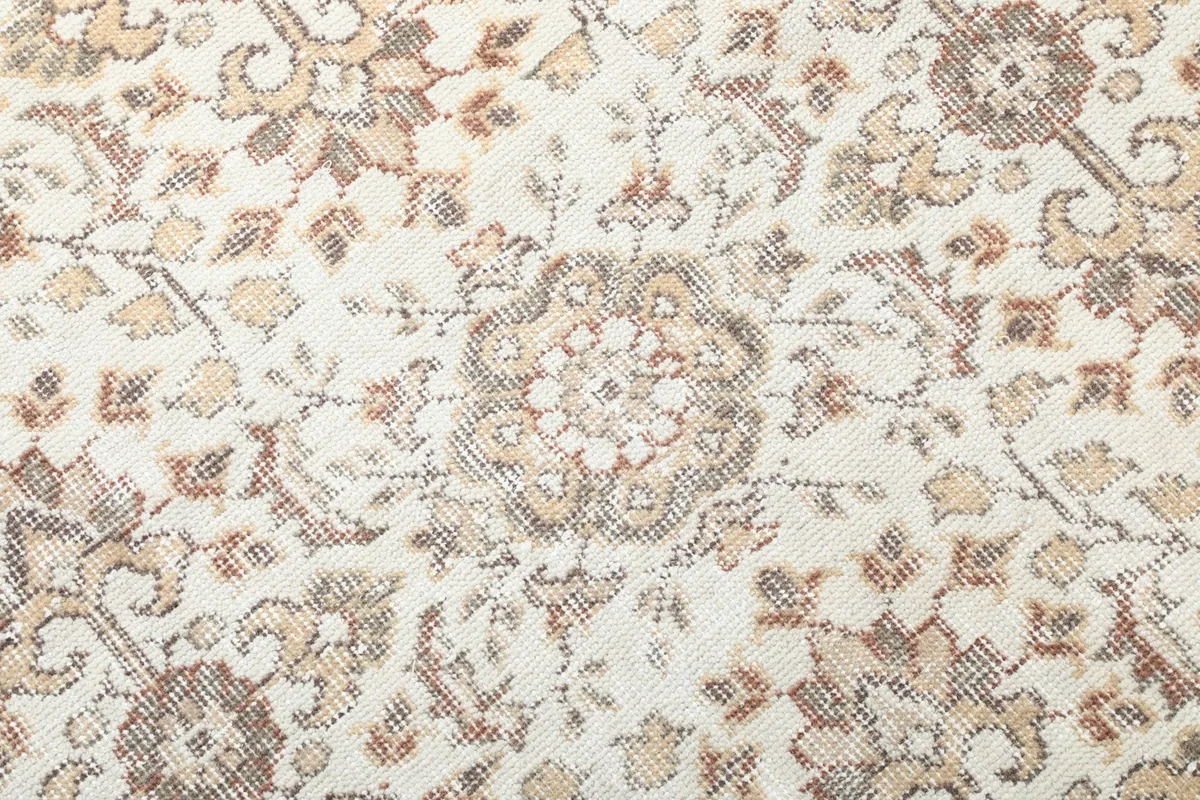 Macro detail of a central floral medallion motif on the ivory background, showing knot detail