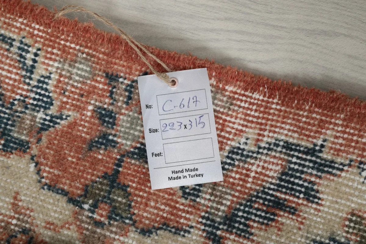 Tag attached to the rug, indicating it is hand-made in Turkey with dimensions 223 x 315 cm.