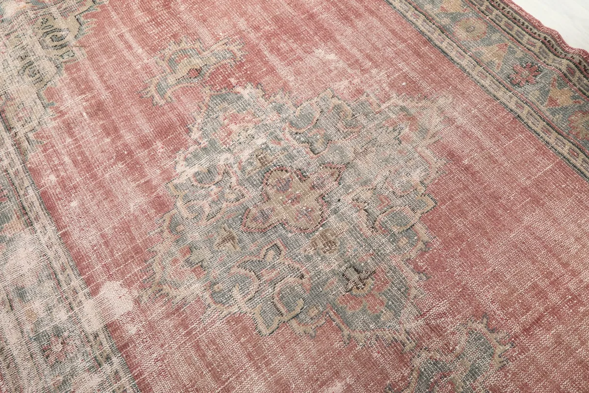 Close-up detail of the central gray medallion and the faded rose field with natural wear