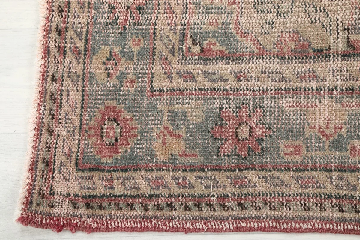 Close-up of the rug's intricate gray and beige border design with floral and geometric motifs