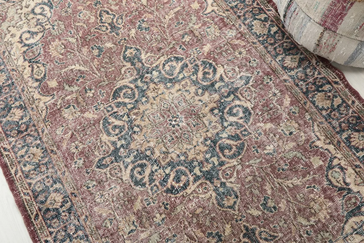 Detailed view of the central navy medallion and surrounding rose and cream floral patterns on the rug.