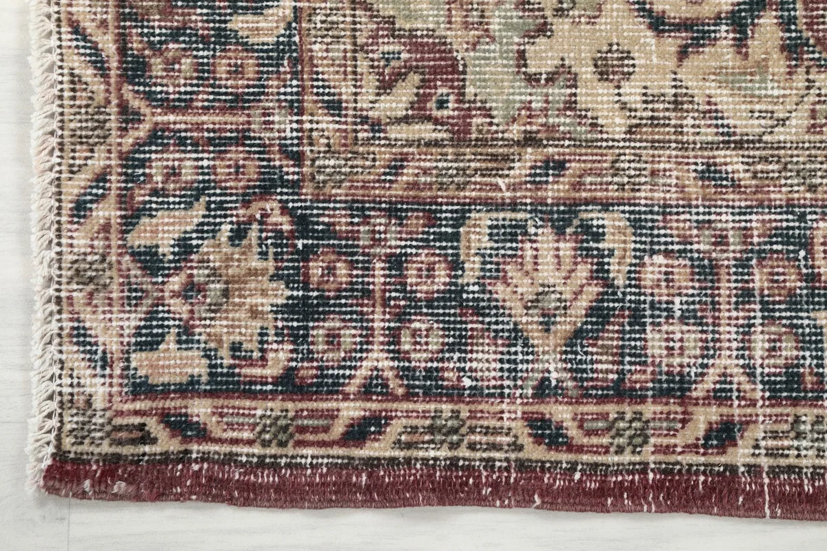 Detail of the navy and cream border design and the edge of the hand-knotted vintage rug.