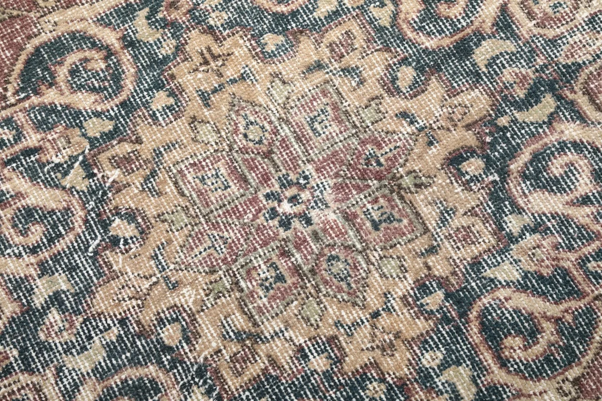 Close-up of the low wool pile, showing the texture and faded colors of the vintage rug.