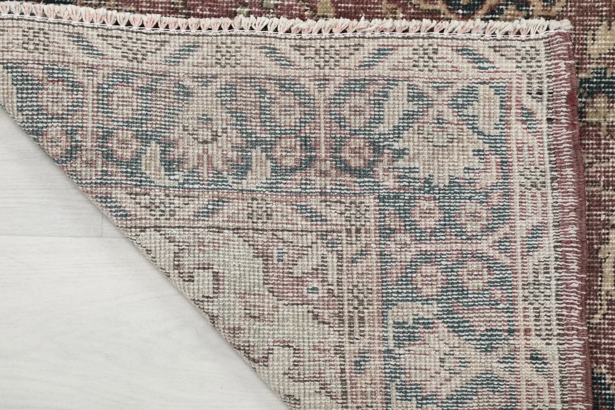 Corner of the rug flipped to reveal the intricate knotting on the cotton foundation and rug's backing.