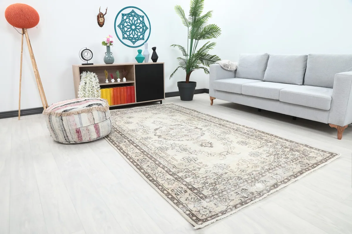 Angle view of the ivory and beige rug in a room, showing its placement relative to a sofa and ottoman