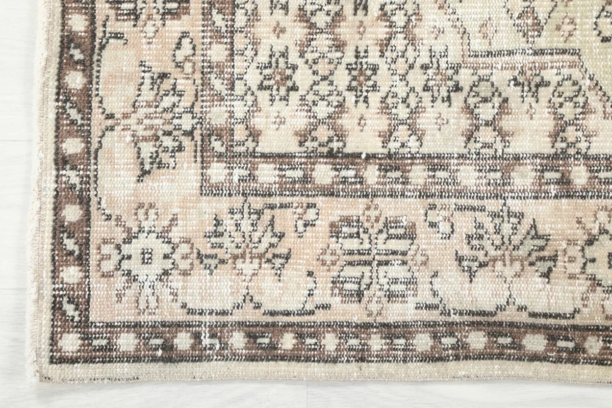 Close-up of the rug's intricate brown and beige border design with geometric motifs