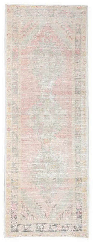 Full overhead view of the vintage pink and gray Anatolian runner rug on a white background.