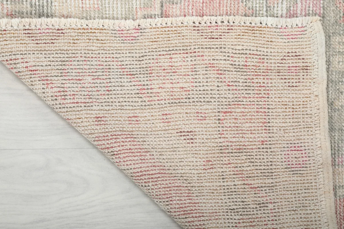 Underside of the rug, revealing the hand-knotted cotton foundation and wool pile knots.
