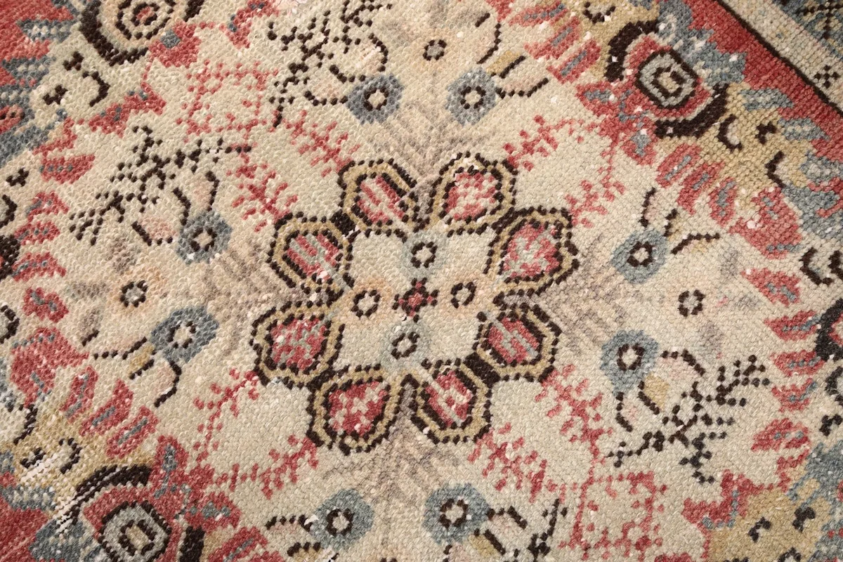 Detailed view of the rug's central ivory medallion with pink, blue, and black motifs