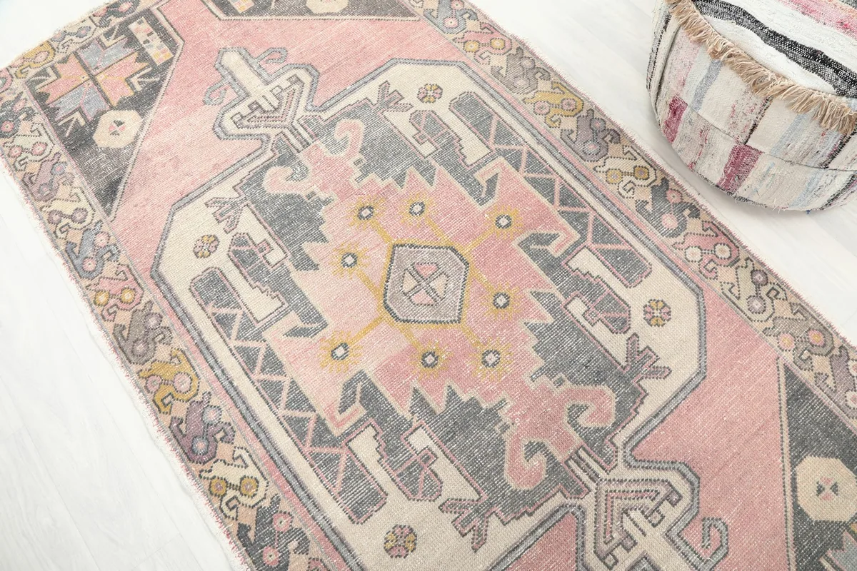 Close angle shot highlighting the central medallion and geometric motifs of the pink vintage rug