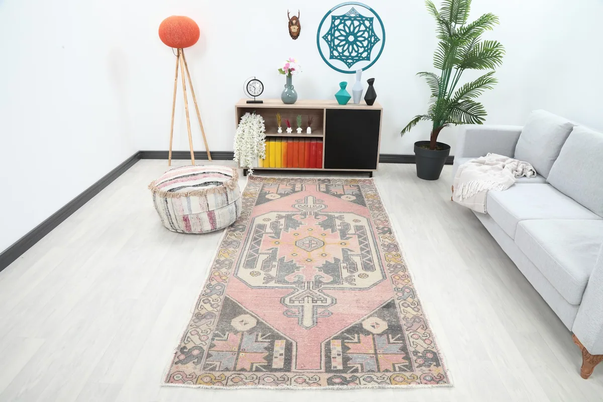 Vintage Anatolian rug with pink and charcoal geometric patterns in a modern living room setting