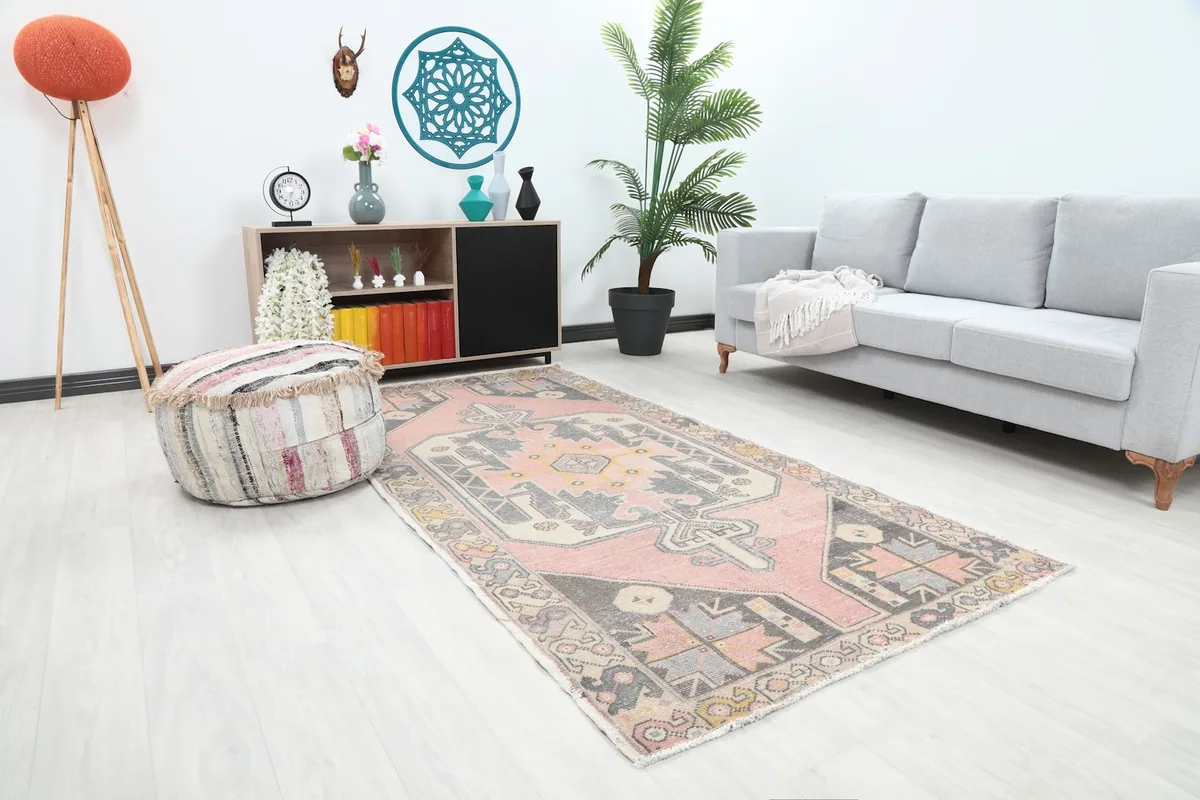 Angle view of the pink and charcoal wool rug in a living room with a gray sofa and white walls