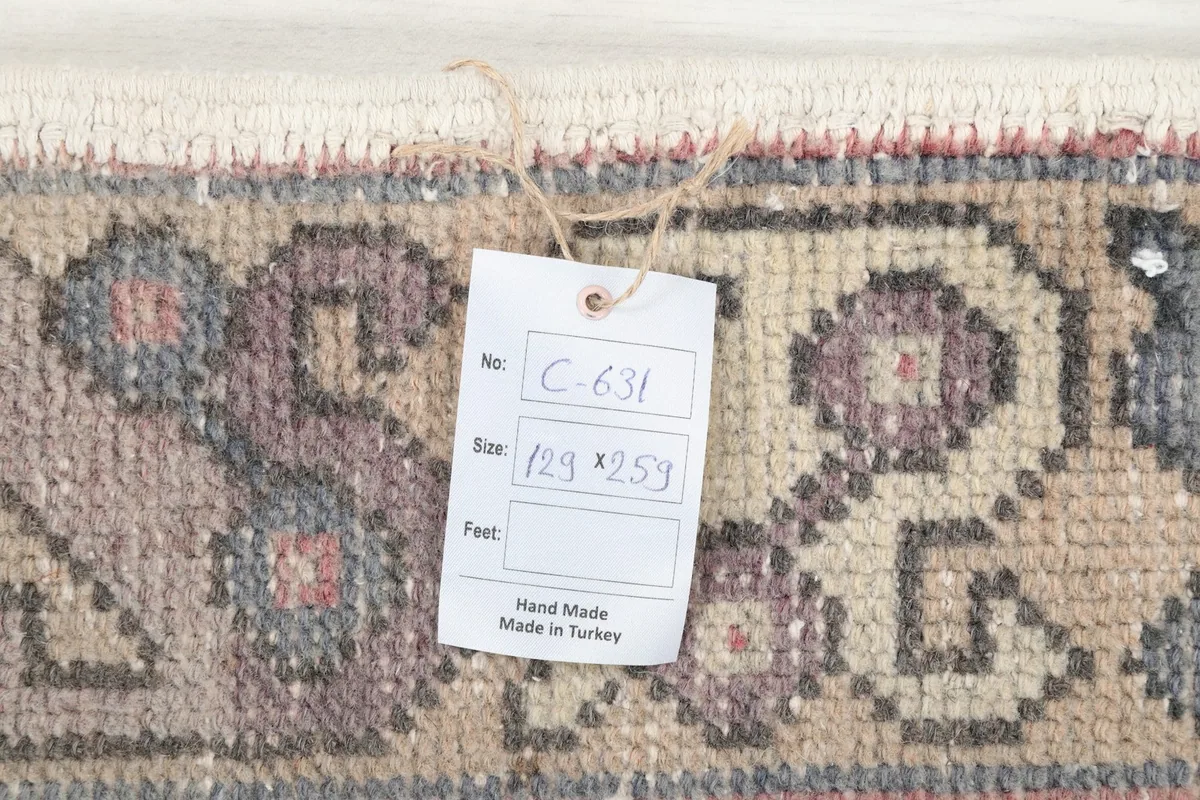 Close-up of a tag on the rug showing the size '129 x 259 cm' and 'Hand Made in Turkey'
