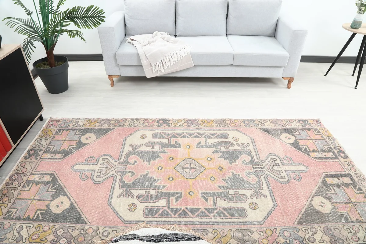 Overhead view of the vintage pink and charcoal rug placed in a room with a sofa