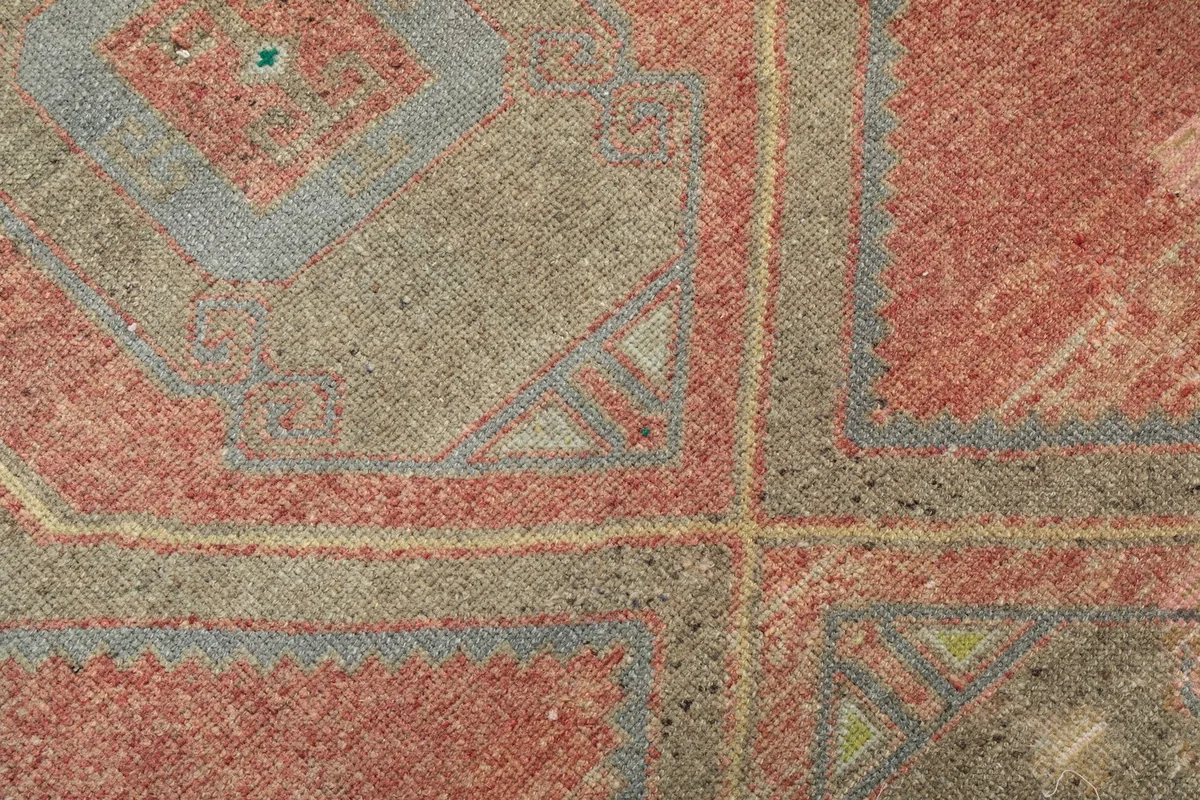 Macro detail of the hand-knotted wool pile, showing the texture and color variations in the rust and blue.