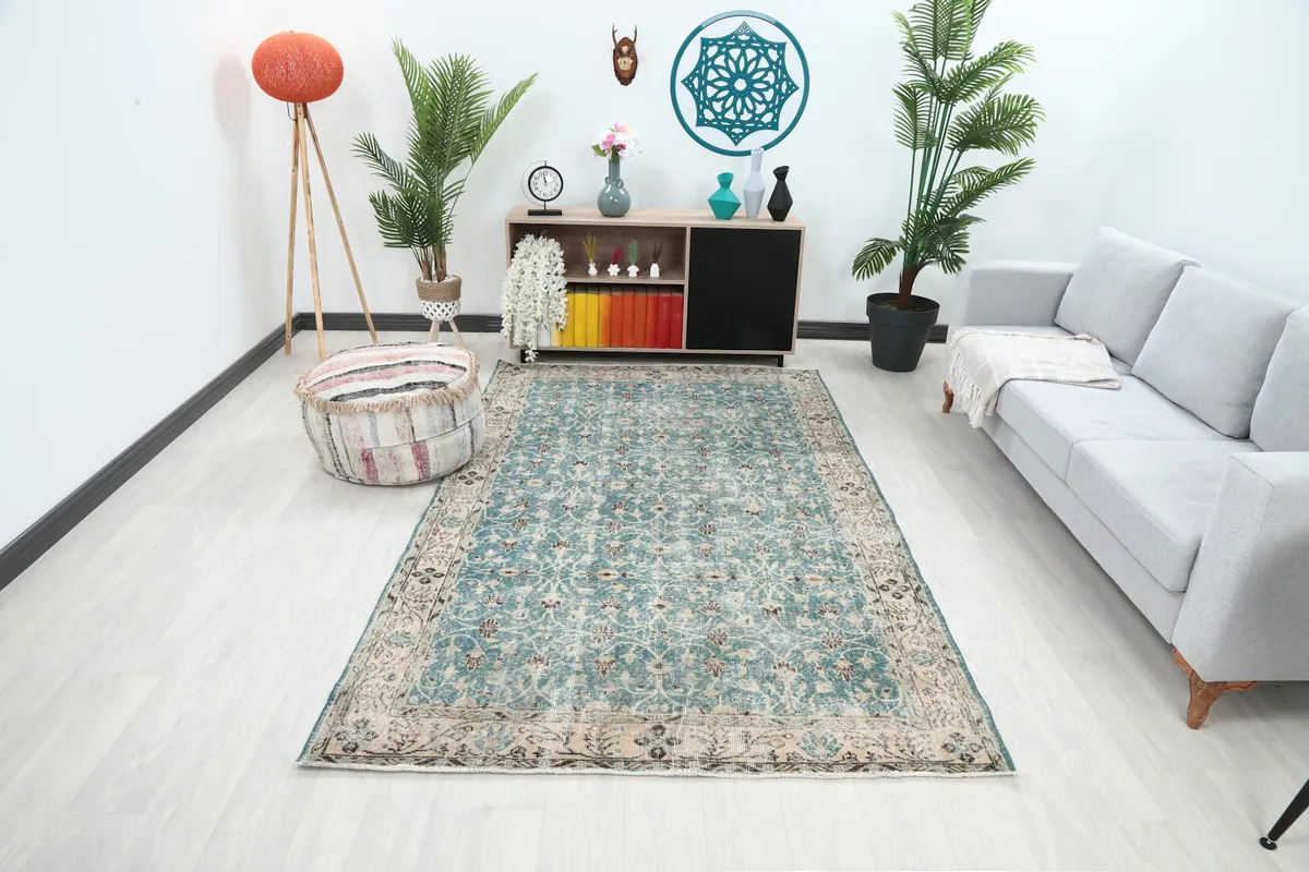 Blue vintage rug placed in a living room setting with a light gray sofa and plants