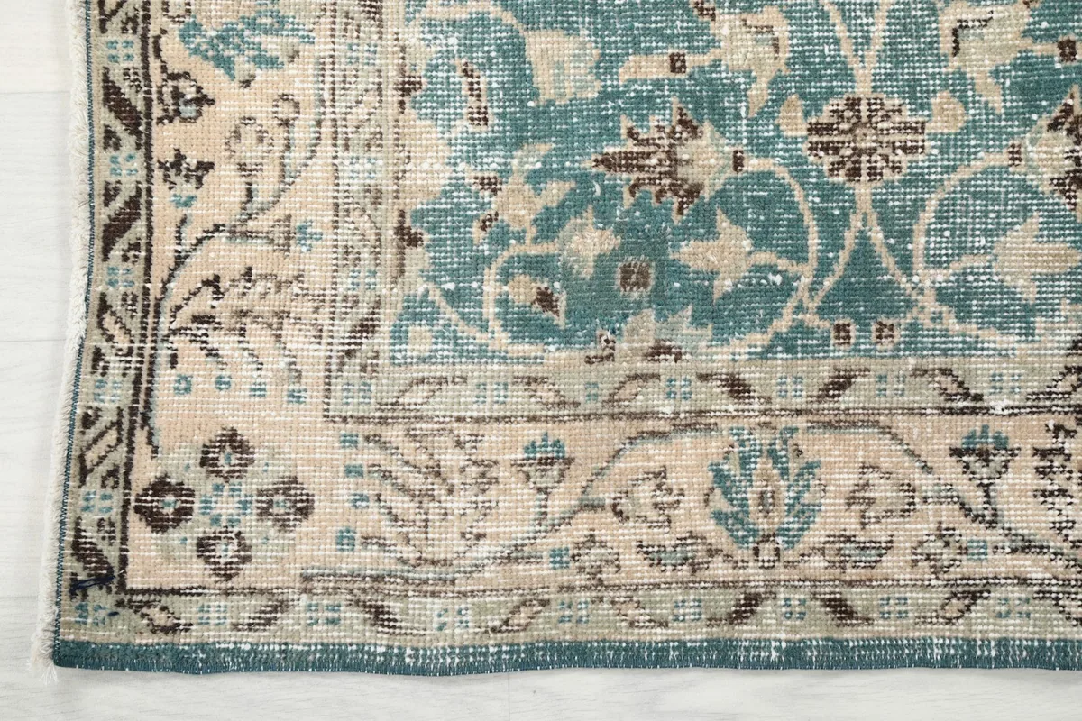 Close-up of the rug's beige border with intricate designs and the main blue field