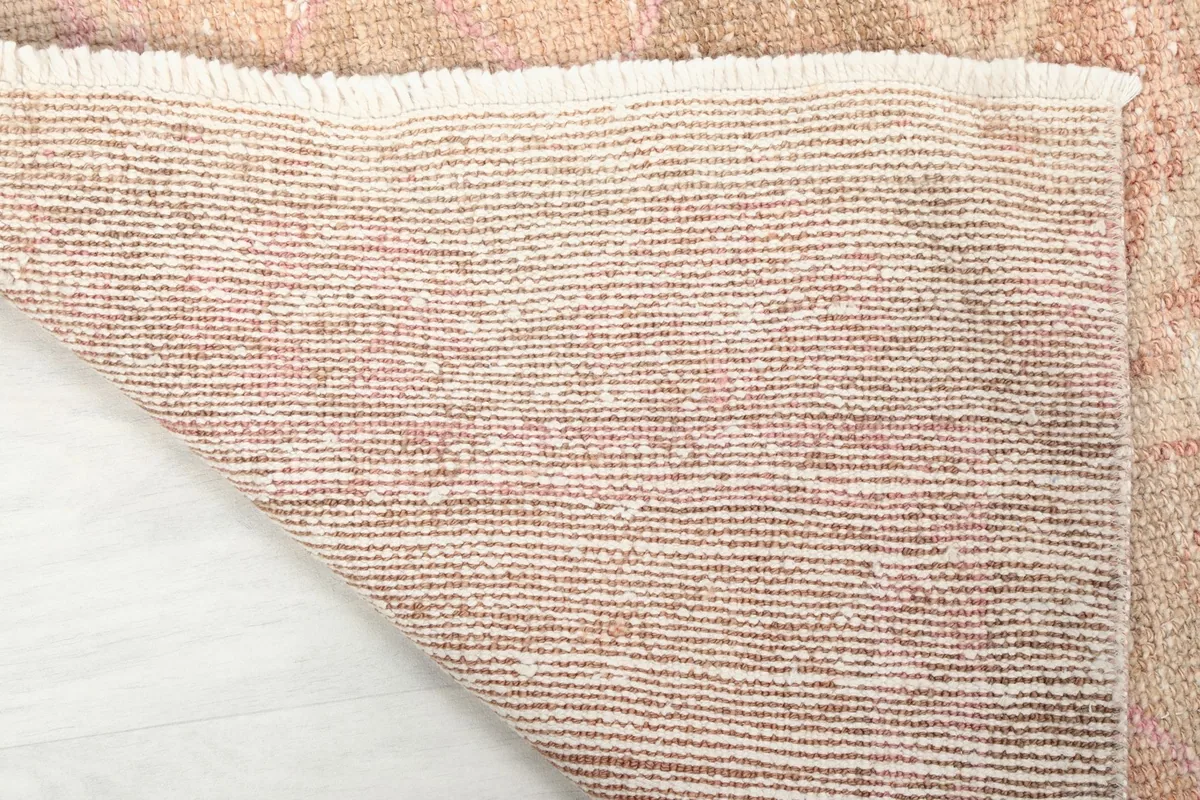 Underside of the runner rug, showing the tightly woven cotton foundation and short fringes.