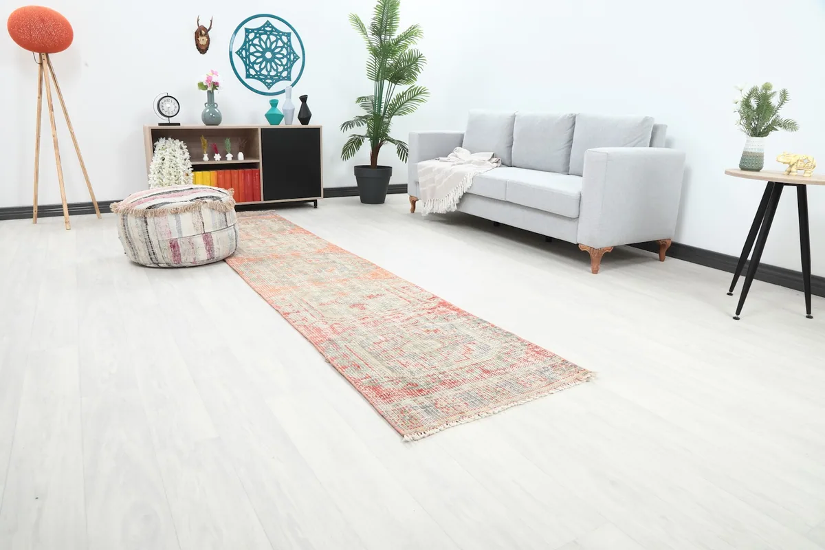 Angle view of the orange and beige runner rug in a room setting, highlighting its placement next to a sofa.