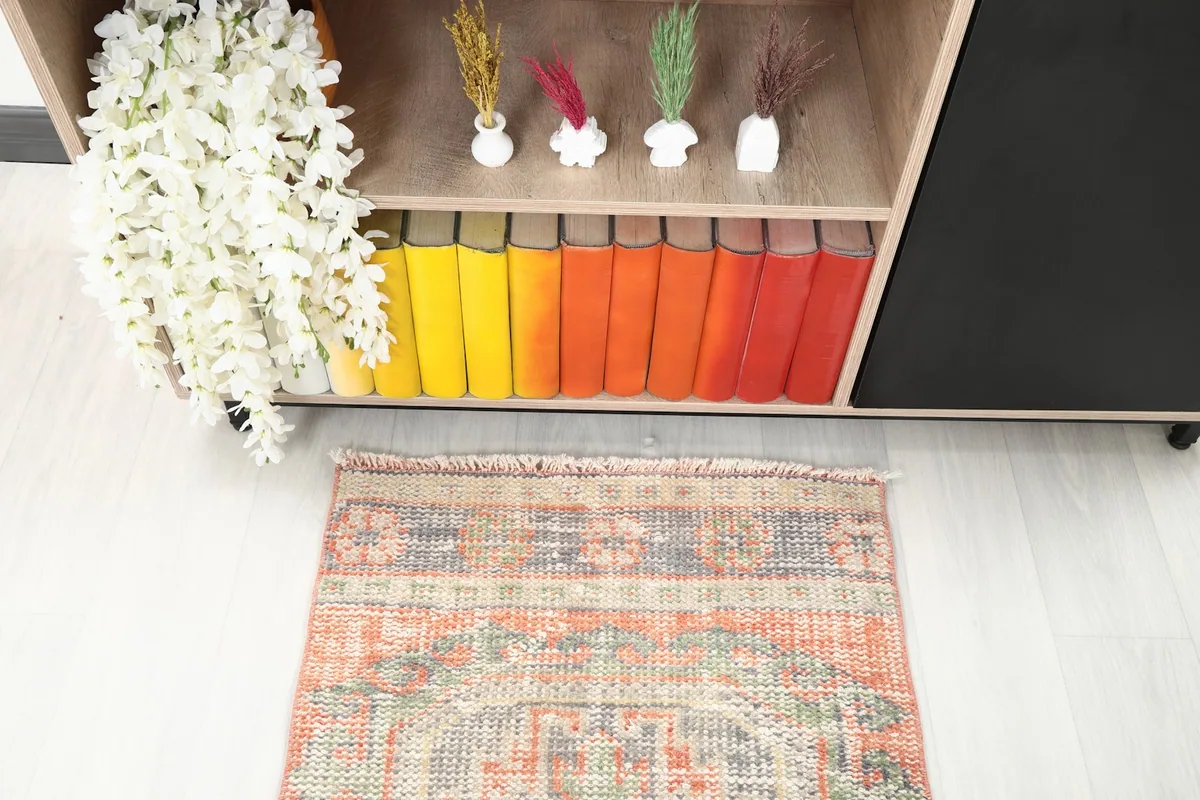 Detail of one end of the runner rug in a room, showcasing its fringe and the colors in the pattern.
