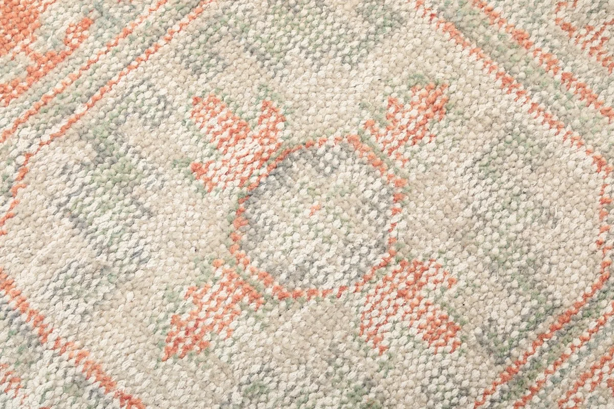 Detailed close-up of the hand-knotted wool pile, revealing the intricate geometric pattern and color variations.
