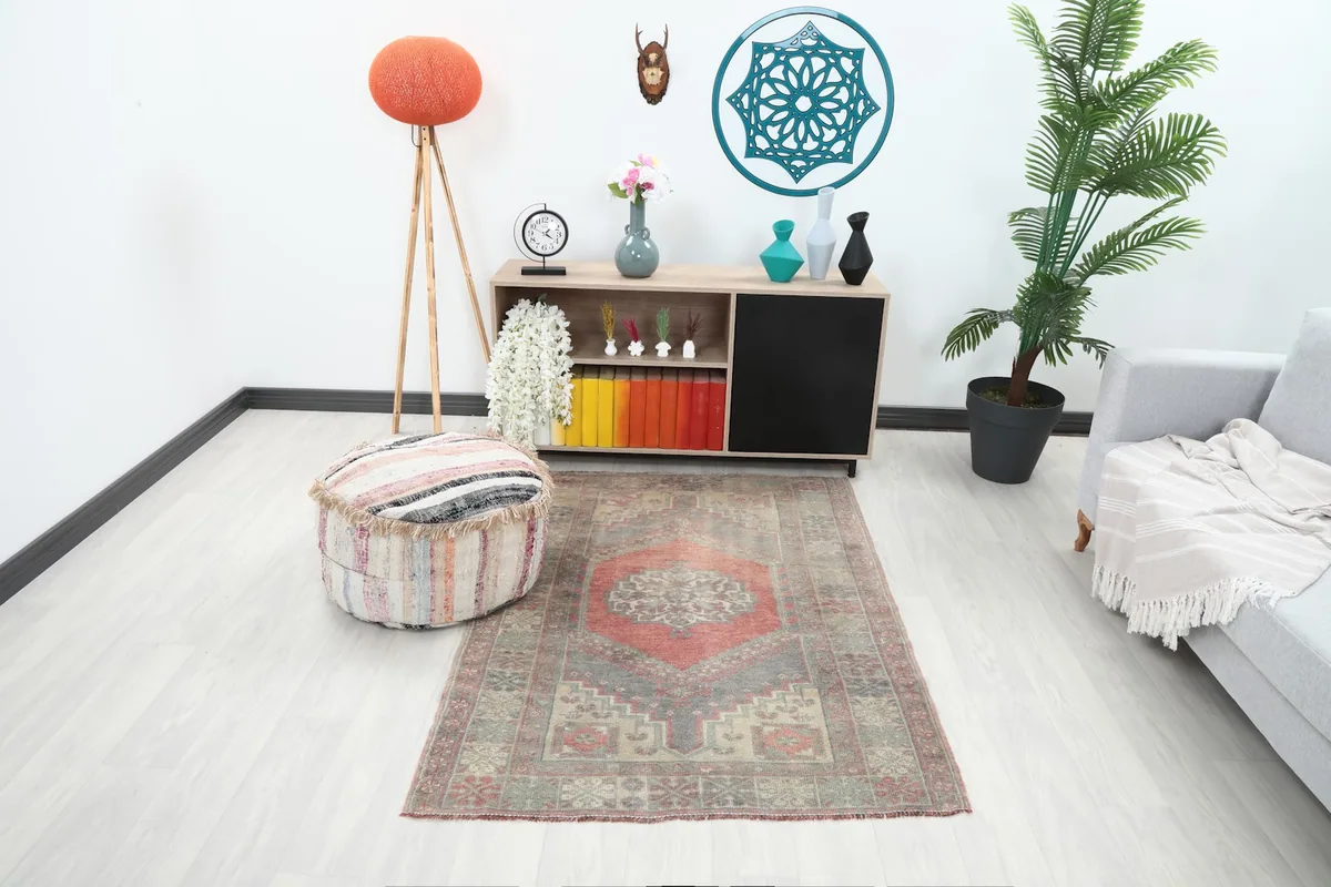 Vintage Anatolian rug displayed in a living room setting with a light-colored couch and wooden furniture.