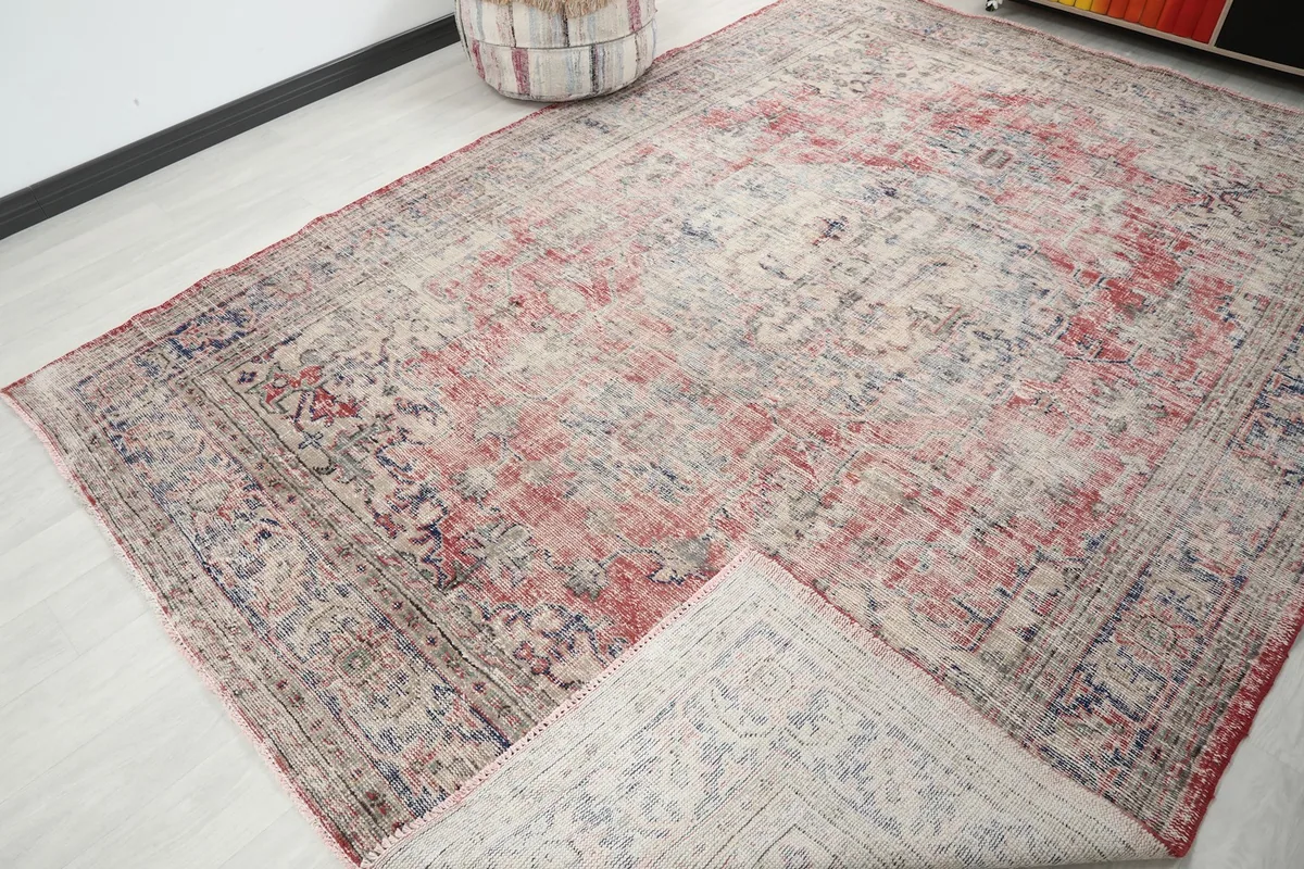 View of the vintage rug partially folded, showing the underside and woven structure