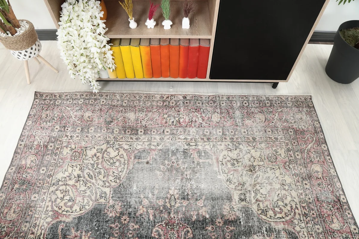 Diagonal view of the rug's surface, highlighting the faded rose and charcoal tones from above.