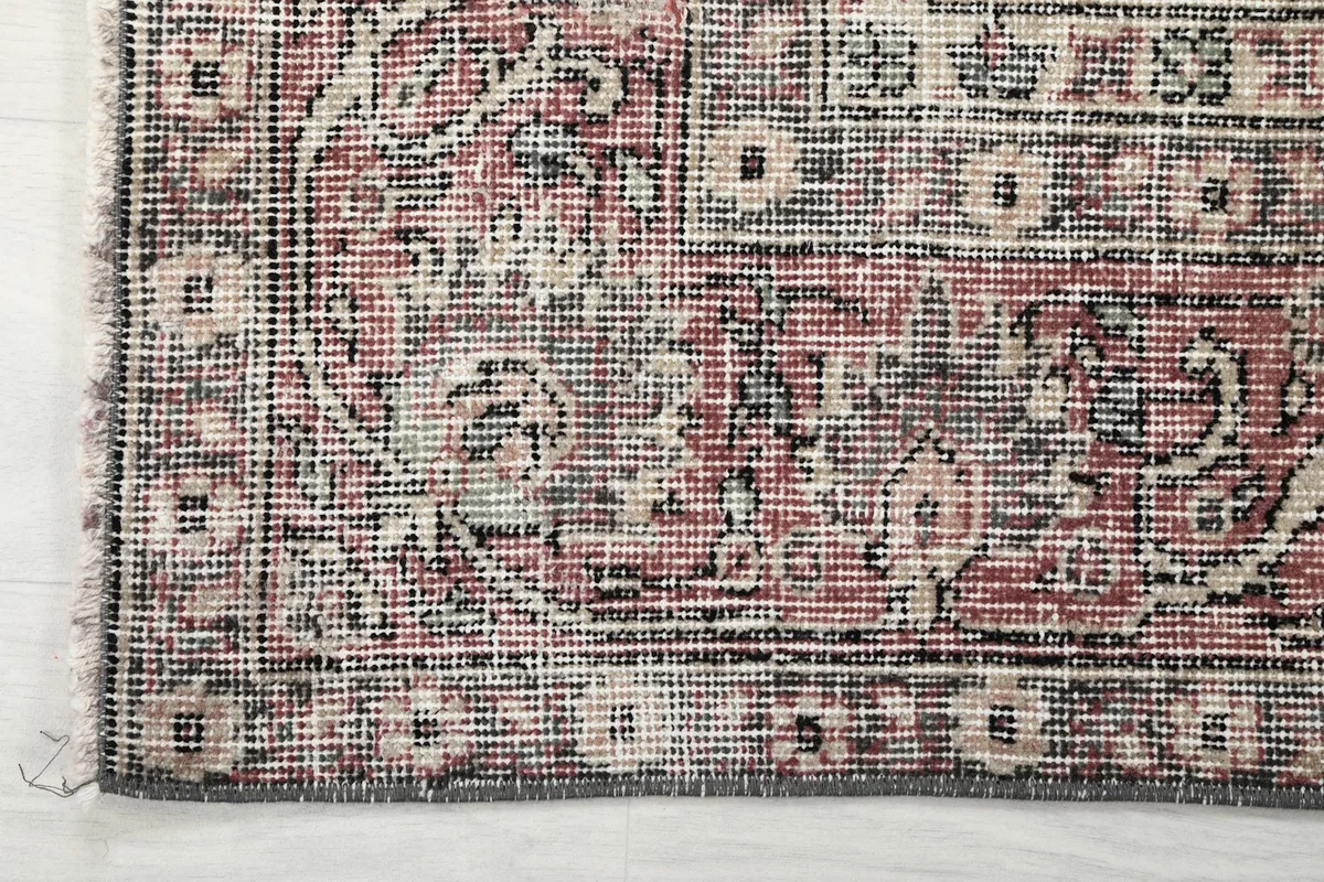Detail of the rug's border and fringe, showing the intricate design and natural wear.