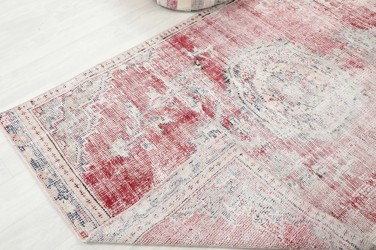 Corner view of the rug, showing a slight fold and the overall distressed appearance of the fibers.