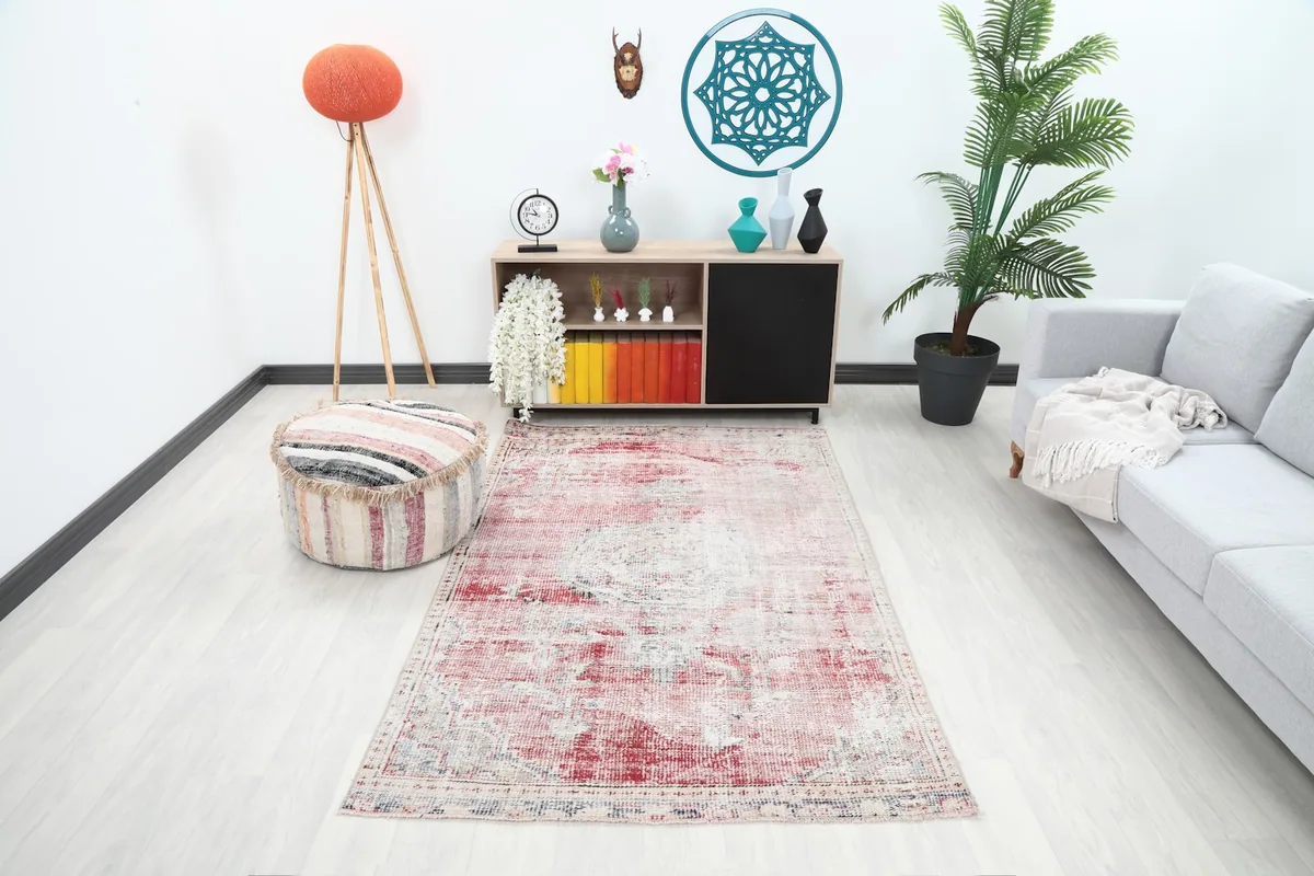 The rose and cream area rug styled in a modern living room setting with a light gray sofa and wooden cabinet.