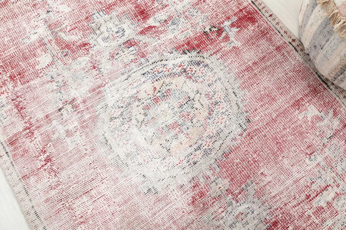 Detailed close-up of the rug's central medallion, revealing the faded patterns and wool texture.