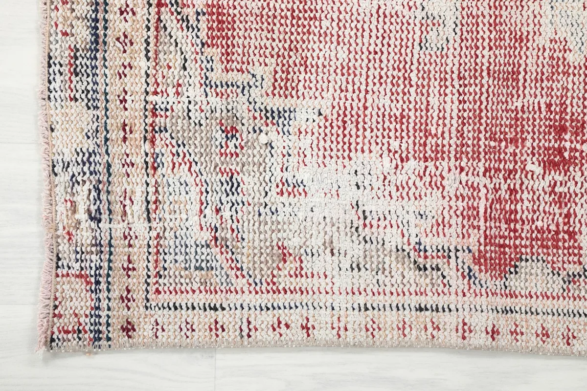 Detail of the rug's border, displaying the geometric patterns and navy accents against the cream field.