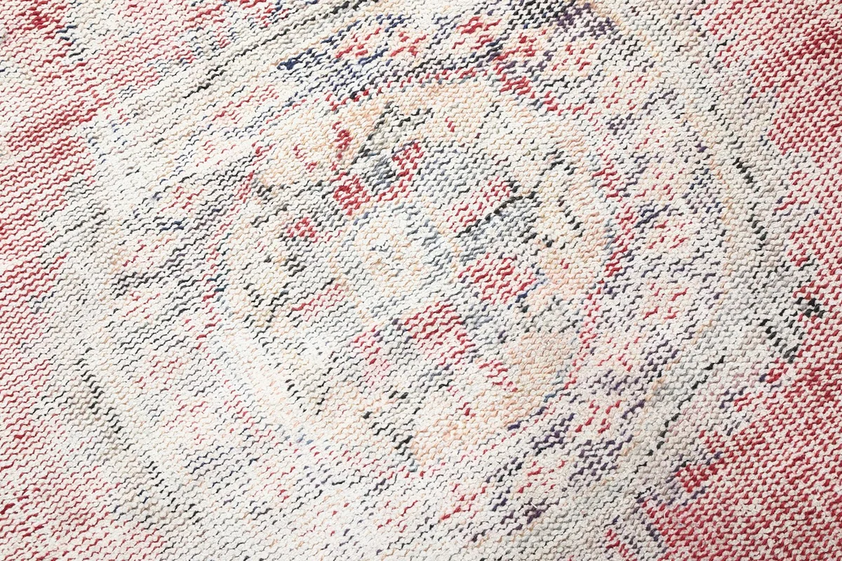 Close-up showing the low pile and hand-knotted wool construction, with visible wear and color blending.