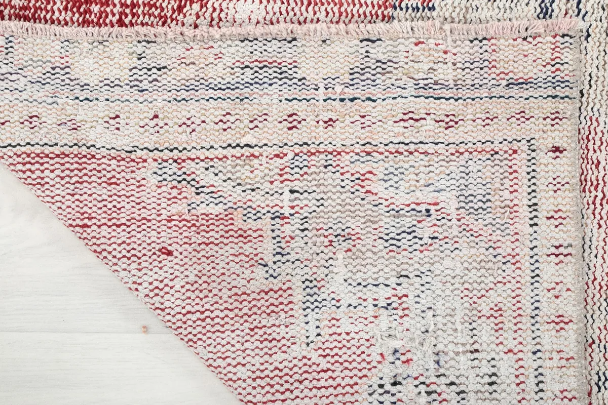 Close-up of the underside of the rug, revealing the hand-knotted cotton foundation and wool knots.