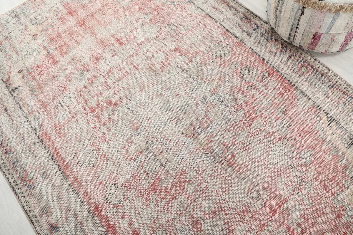 Detailed view of the rug's surface, showing the faded rose and cream pile texture