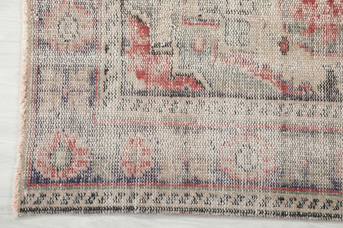Detail of the rug's border, showcasing the intricate geometric motifs in gray and blue