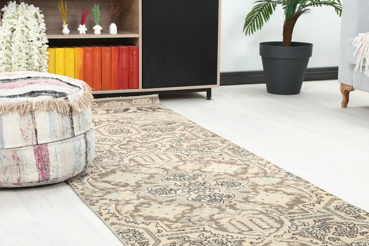 Close-up view of the runner rug in a room, highlighting its beige and brown floral motifs near a decorative pouf