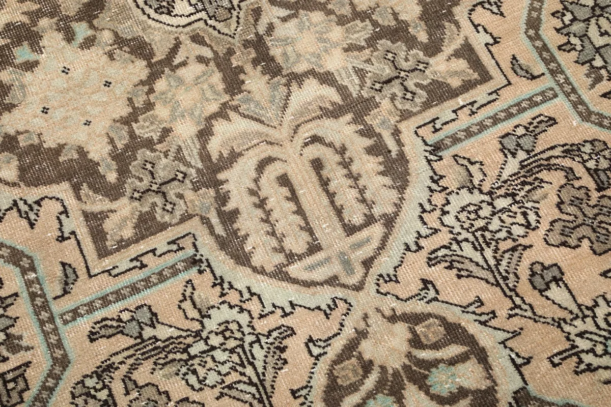 Close-up detail of the hand-knotted wool pile, showing the texture and faded floral and geometric motifs