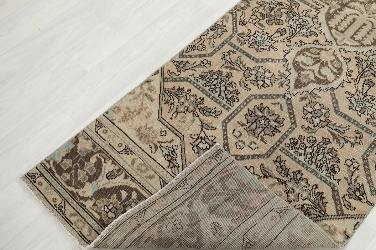 Corner of the runner rug folded to reveal the cotton foundation and the reverse side of the hand-knotting