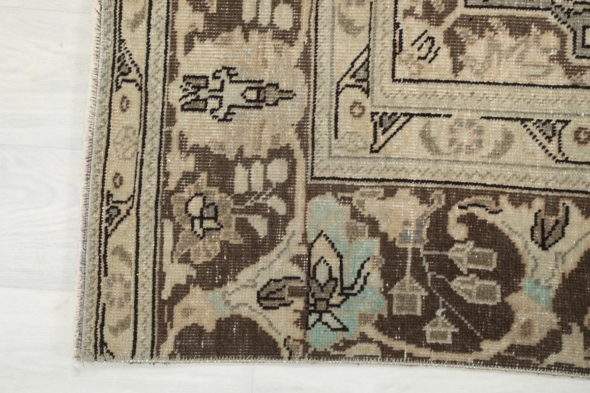 Detail of the rug's border design and corner with visible wear and patina