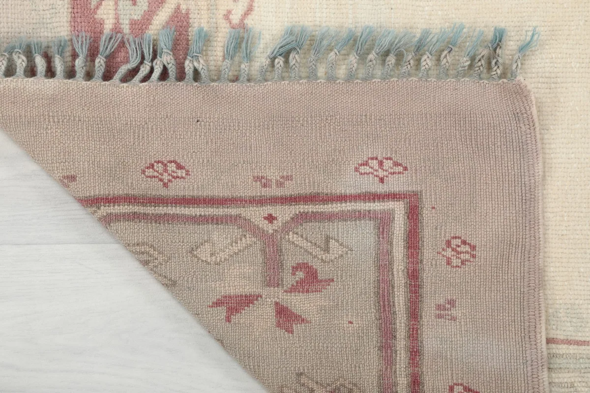 Underside view of the rug, showing the hand-knotted cotton foundation and fringe