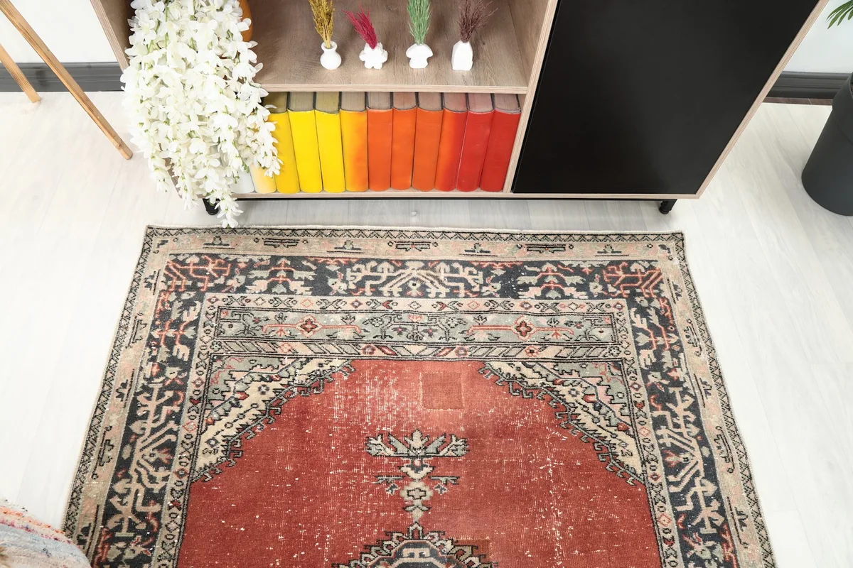 Upper section of the rust rug, highlighting the border and field details.