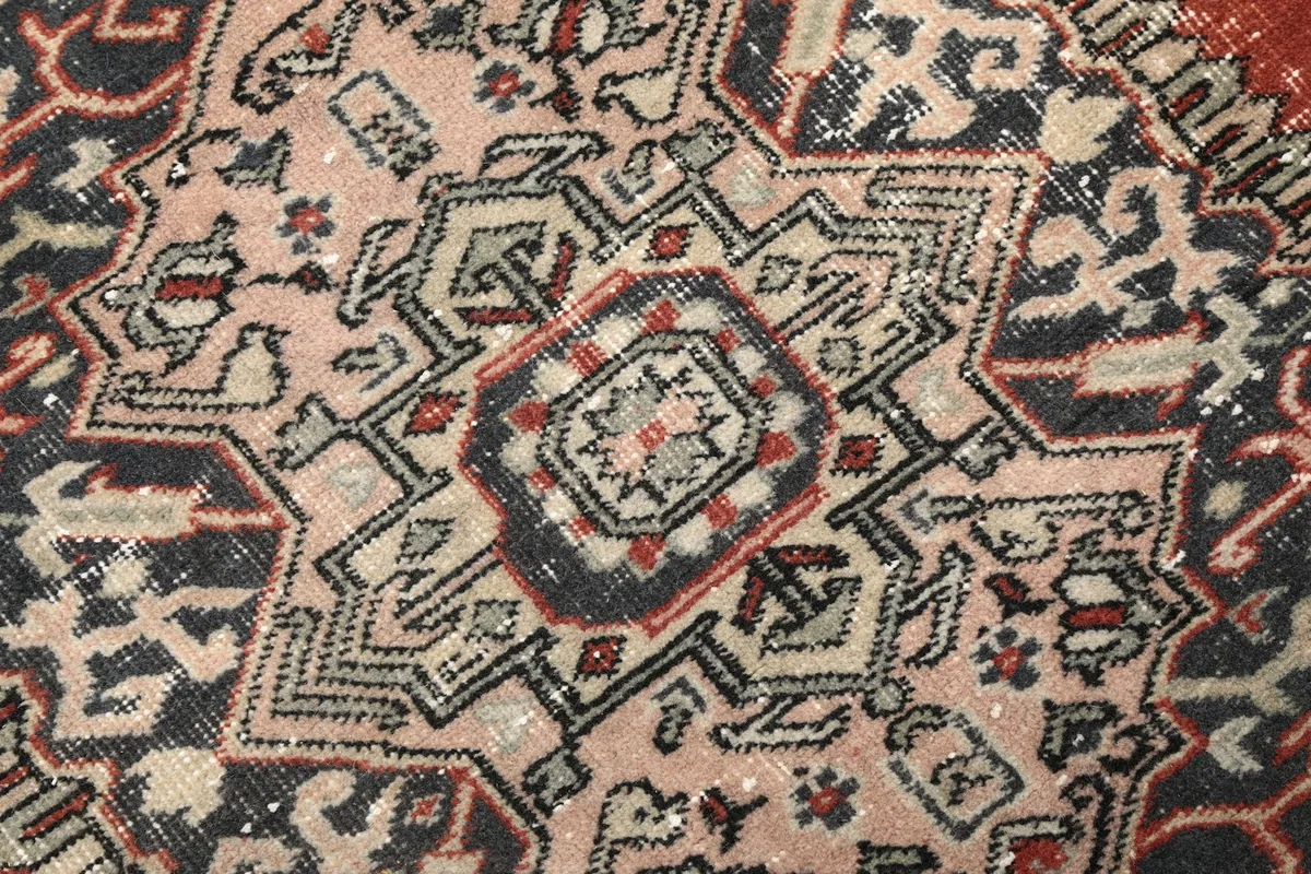 Close-up of the medallion's intricate geometric patterns in navy, beige, and pink tones.