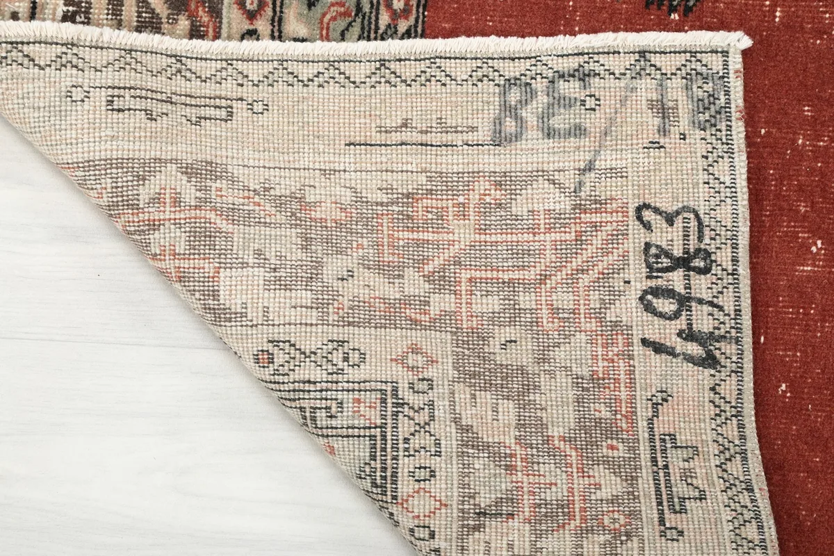 Close-up of the rug's back, showing the hand-knotted foundation and some markings.