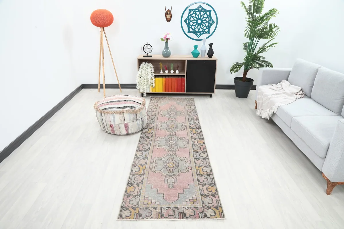 Vintage pink and gray runner rug placed in a modern living room setting with a sofa and decor.
