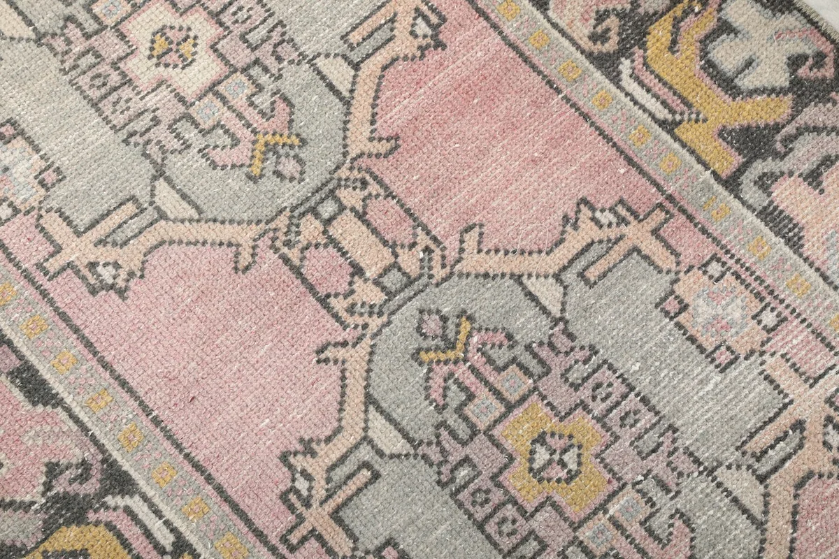 Close-up of the hand-knotted wool pile, showing the texture and muted colors of the geometric pattern.