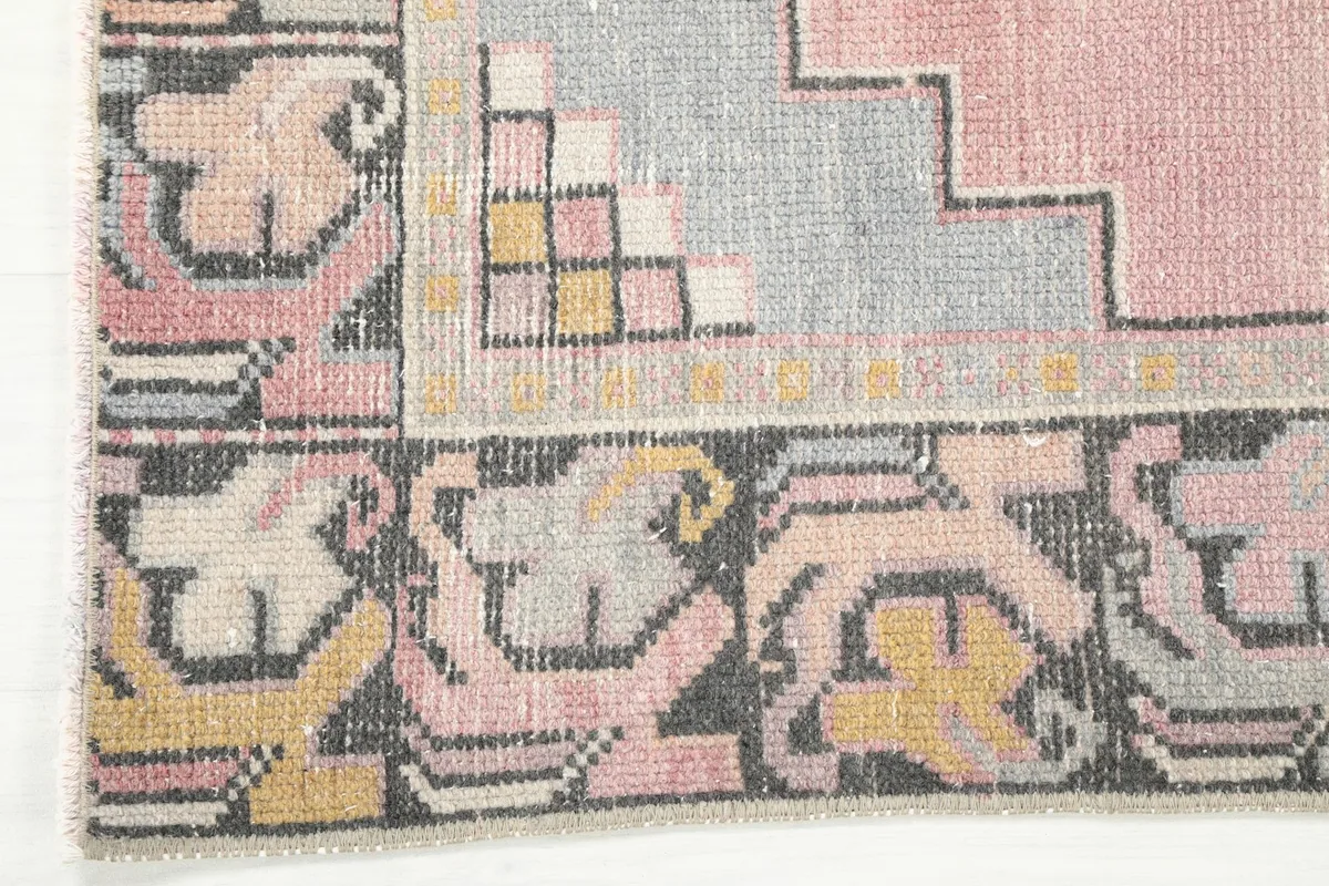 Close-up of the intricate border design with black, yellow, pink, and gray motifs.